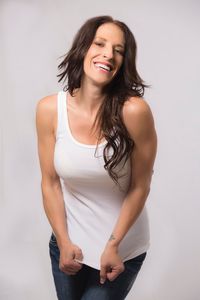 Portrait of happy woman with long hair standing against white background