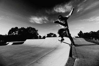 Man skateboarding at park against sky