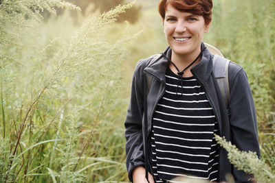 Portrait of young woman standing against plants