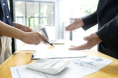 Cropped image of man holding paper with table