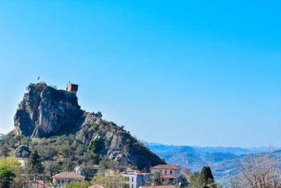 Buildings and mountains against clear blue sky