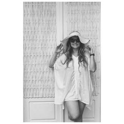 Portrait of woman wearing hat standing against wall