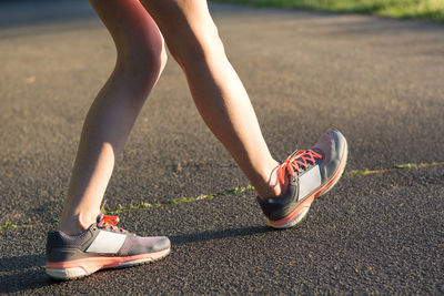 Low section of woman walking on road