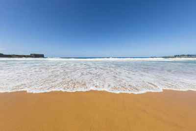 Scenic view of beach against clear blue sky