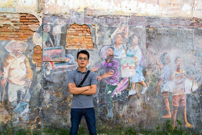 Portrait of a smiling young man standing against wall