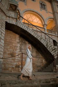 Full length of woman standing by building