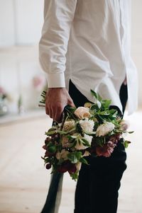 Midsection of man holding flower bouquet