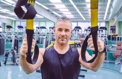 Portrait of man holding resistance band at gym