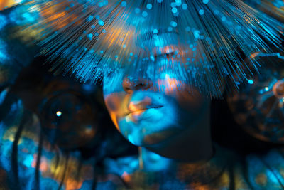 Digital composite image of woman and plasma ball with fiber optics