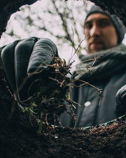 Close-up of young man holding insect against tree