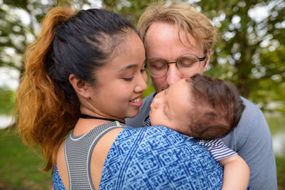 Cheerful parent embracing baby outdoors