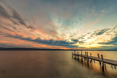 Pier on sea against sky during sunset