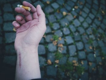 Close-up of a hand with a scar holding a cigarette