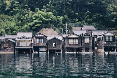 Houses by river against buildings