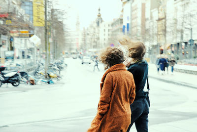 Rear view of women walking on city street during winter