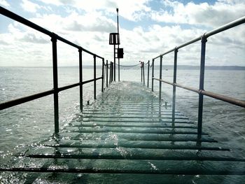 Pier on sea against cloudy sky