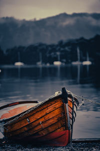 Boat moored in lake against sky during sunset