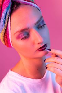 Thoughtful young woman wearing make-up and towel while looking away against pink background