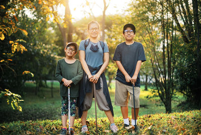 Full length of smiling boy on plants against trees
