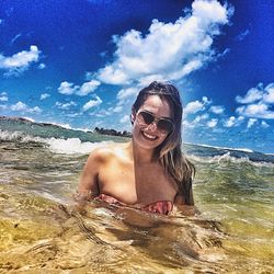 Portrait of young woman wearing sunglasses against sky