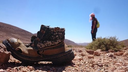 Man looking at abandoned shoe against sky