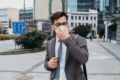 Business man standing on city street with protective face mask.