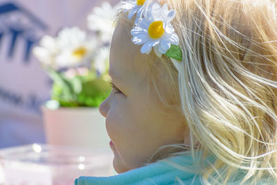 Close-up of girl with flowers against blurred background