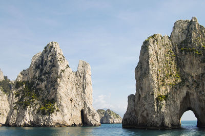 Rock formations by sea against sky