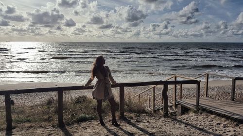 Woman standing by railing at beach