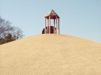 Low angle view of gazebo on hill against clear blue sky