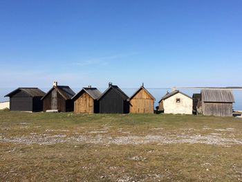 Houses on field against clear blue sky