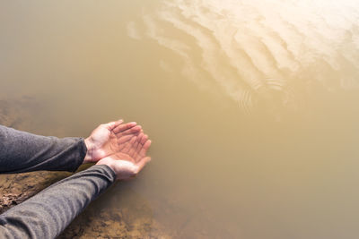 Cropped hands cupped in lake