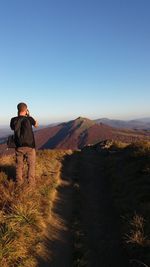 Rear view of man looking at mountain against clear sky