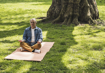 Retired senior man meditating on exercise mat at park