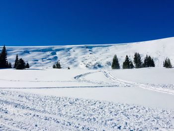 Scenic view of snow covered landscape against clear blue sky