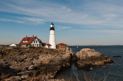 Lighthouse on coast against cloudy sky