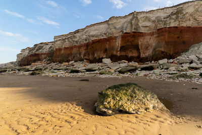 Rock formations on beach against sky