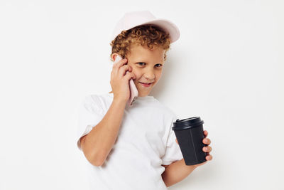 Boy talking on smart phone against white background