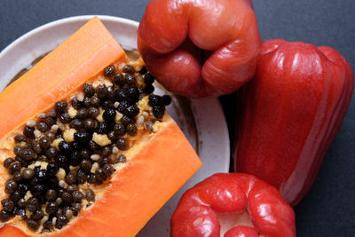 High angle view of water apples and halved papaya in plate on black table