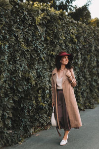 A happy single woman in elegant clothes walks in an fall park and in the forest in autumn outdoors