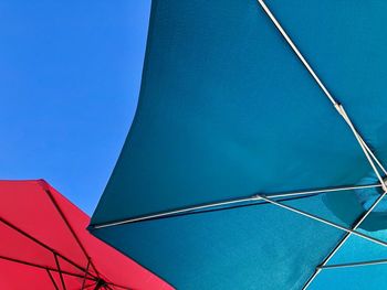 Low angle view of parasol against clear blue sky