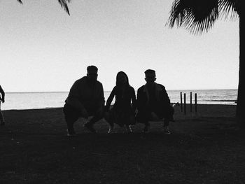 People sitting on beach against clear sky