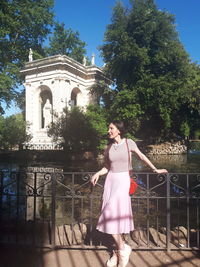 Woman standing by railing against trees