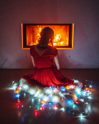 Rear view of woman standing against illuminated light