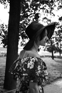 Midsection of woman standing by tree trunk