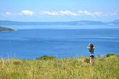 Rear view of man standing in sea against sky