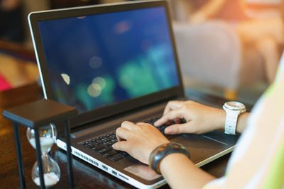 Cropped image of woman using laptop at table