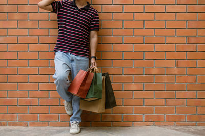 Full length of boy standing against brick wall