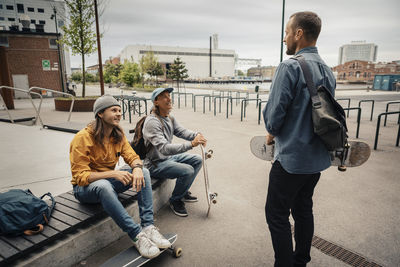 Full length of men sitting on sidewalk in city