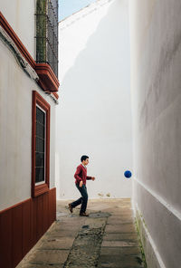 Side view of boy standing by building